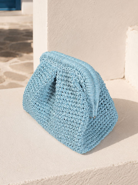 A light blue crocheted raffia clutch bag with a fringed top handle.