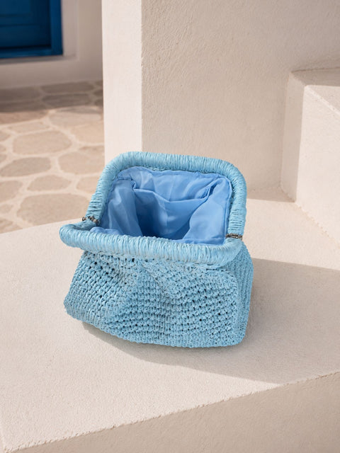 A light blue woven raffia clutch bag with a matching blue fabric lining. 