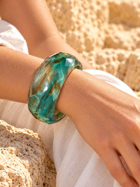 A chunky, faceted bangle bracelet made of translucent aqua and brown swirls.
