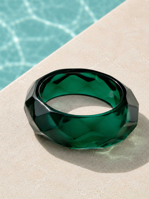 Glossy green faceted acrylic bangle displayed beside a swimming pool