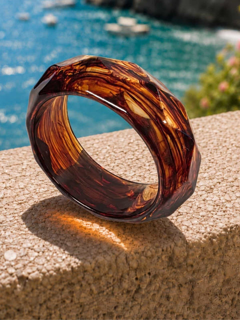 Mavi wide acrylic bangle featuring a sculpted faceted surface and warm brown tones