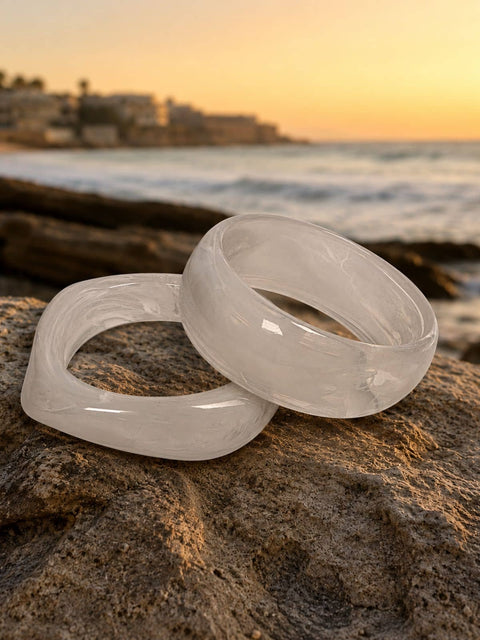 Square white marble acrylic bangle with rounded corners displayed against a coastal sunset backdrop