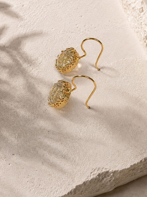 Side view of gold hook earrings showing faceted clear stones with gold flecks inside.