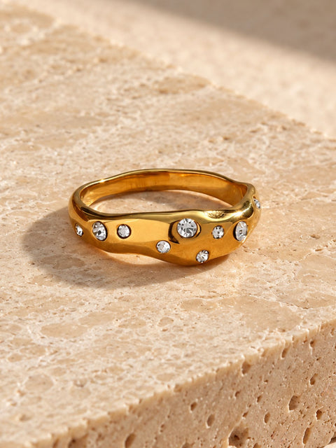 Modern gold tone ring with a polished finish, flowing wave shape and scattered crystal detailing
