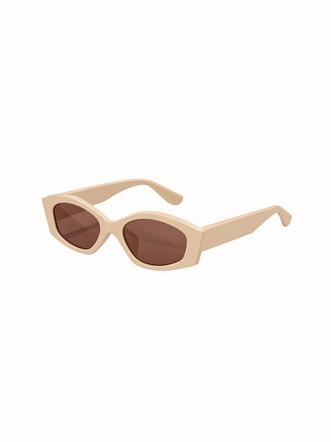 A pair of chunky, oversized cat-eye sunglasses with a matte beige frame and light brown lenses