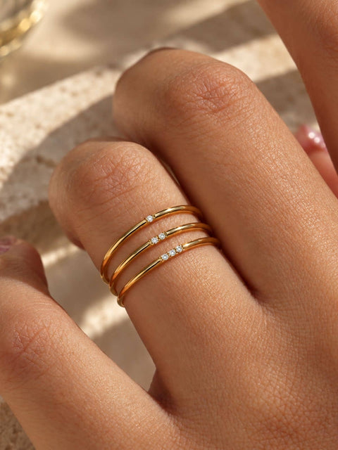 Three delicate gold rings, each adorned with a small row of clear pavé-set stones
