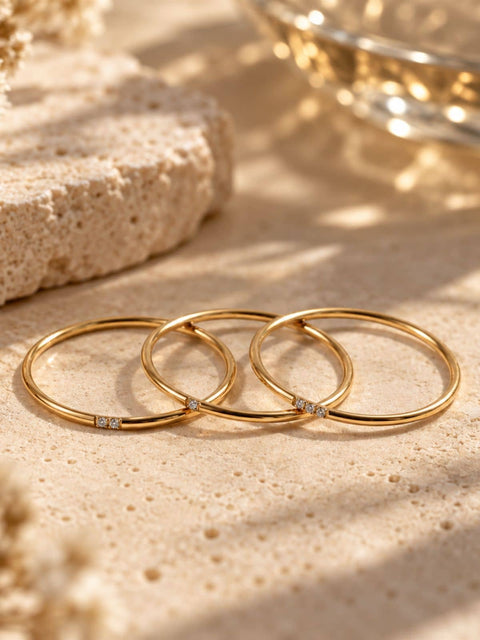 Set of three thin gold rings with small clear gemstone accents set in each ring